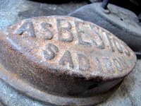 Closeup view of a piece of iron with the word "Abestos" molded onto it