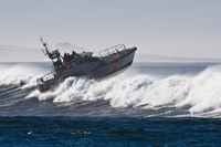 Daytime view of a Coast Guard vessel pushing through high surf