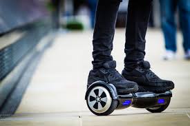 Closeup image of someone standing on a hoverboard on an urban sidewalk