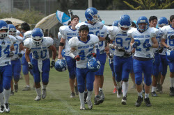 Youth football players run onto the field before a game
